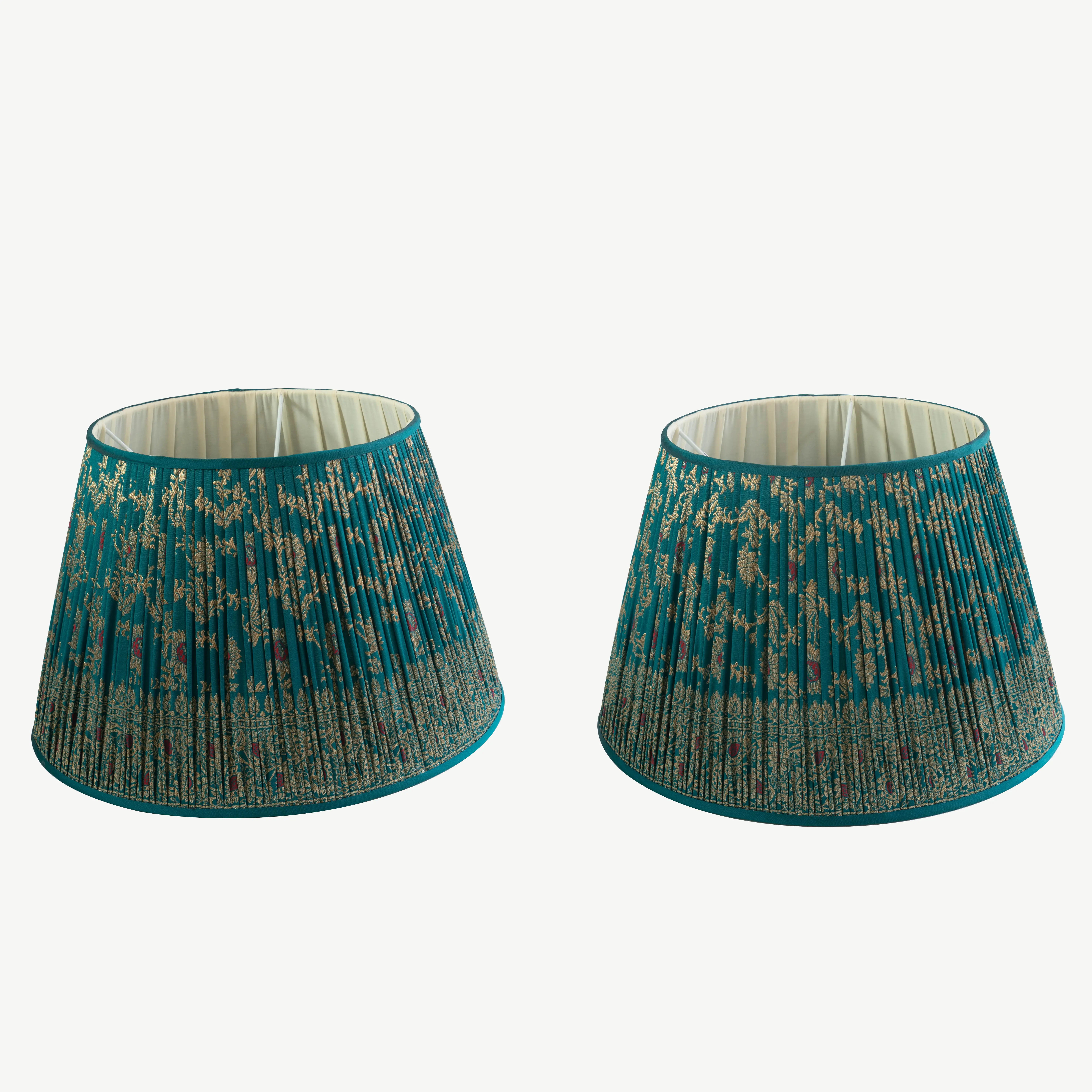 A pair of turquoise lampshades with metallic gold detailing