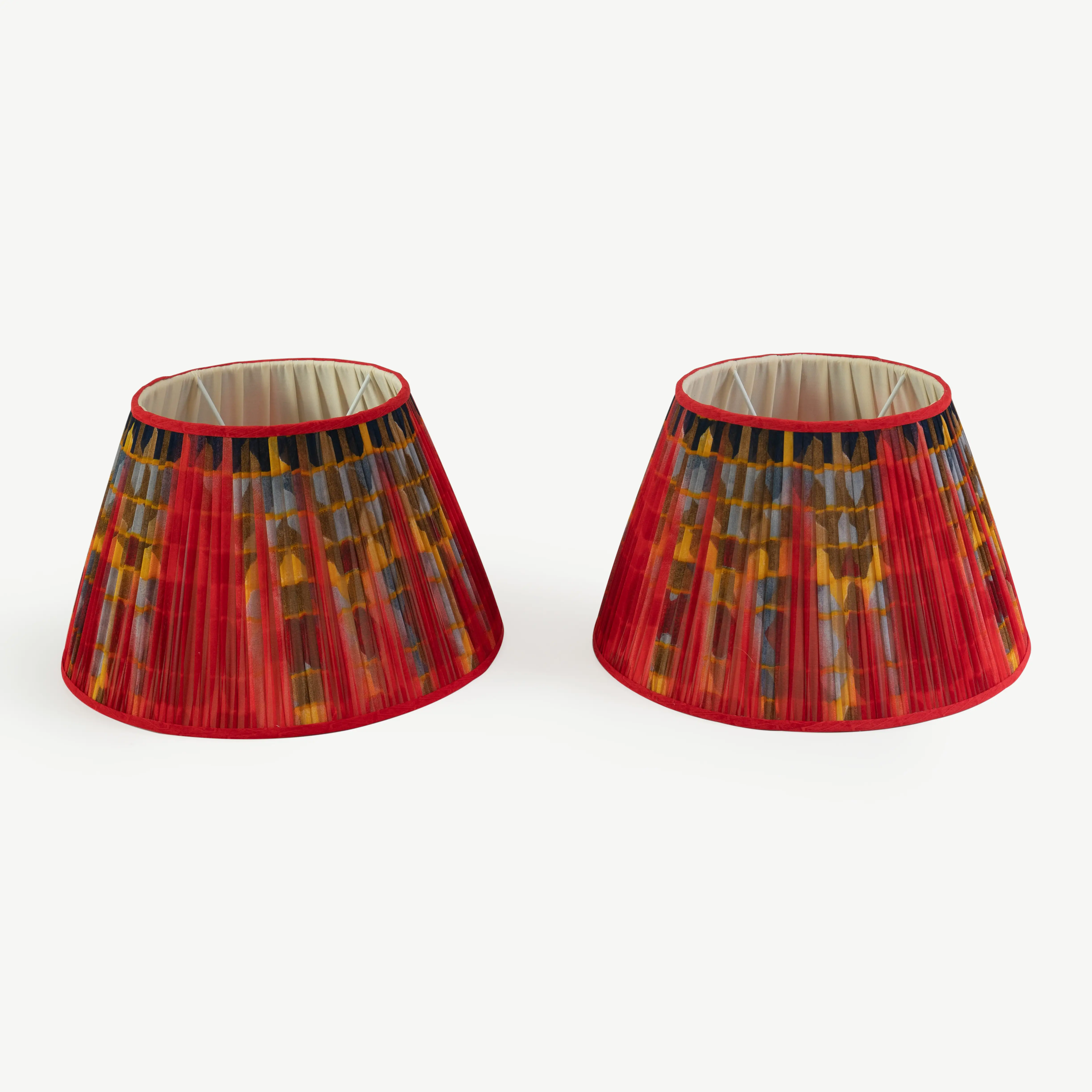 A pair of red lampshades with a yellow, black and blue geometric pattern