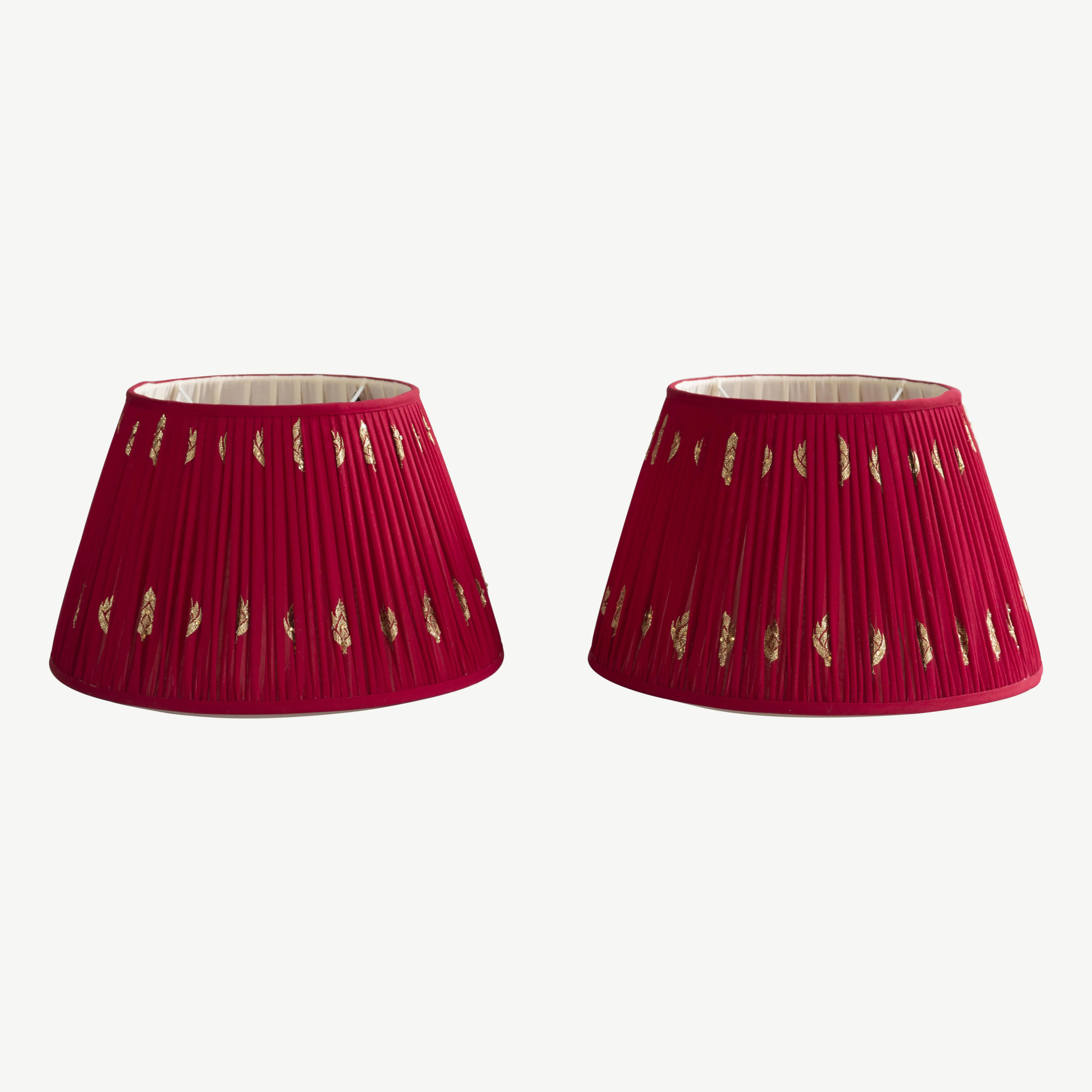 A pair of red lampshades with gold embellishments